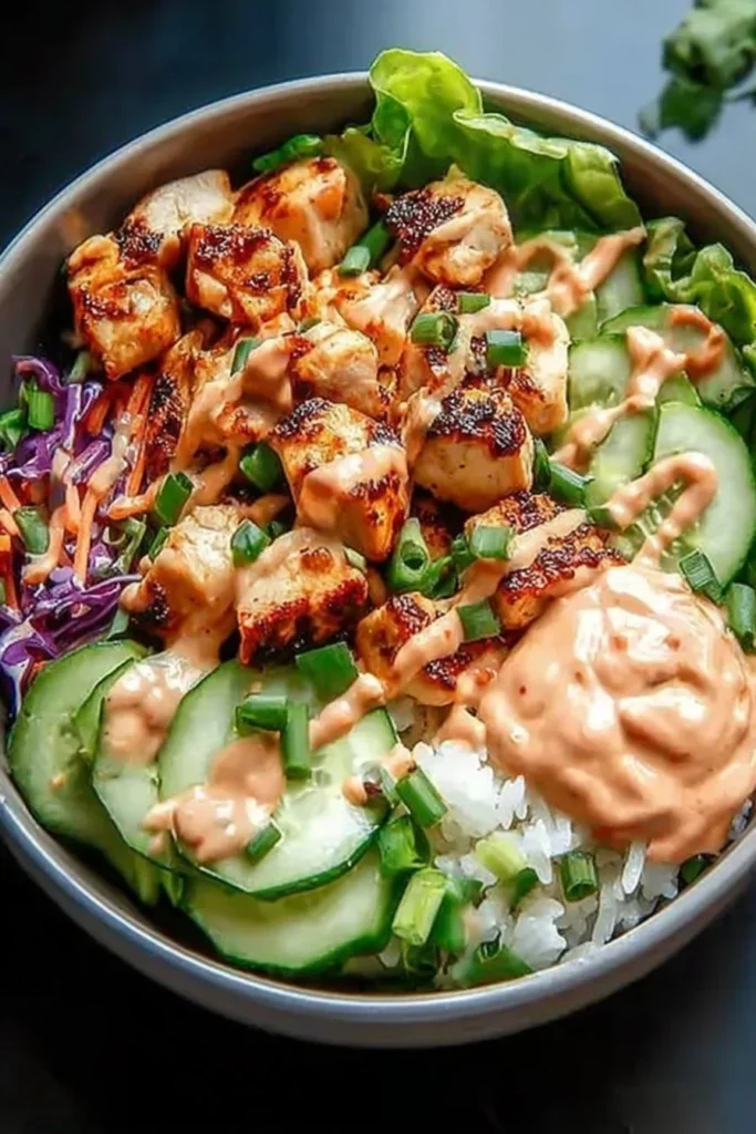 Delicious Bang Bang Chicken Bowl topped with fresh vegetables and creamy sauce